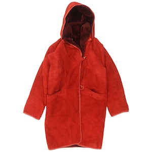 May include: A long-sleeved, knee-length coat in a vibrant red color. The coat features a hood, a soft dark red interior lining, and a front closure with two visible toggle-style buttons. The outer material has a smooth, suede-like texture.
