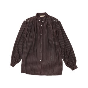 May include: A dark brown long-sleeve shirt featuring thin vertical white pinstripes, a button-down front, and gathered fabric details at the shoulders. The shirt includes a small white label at the collar with the text CLANI printed in black.