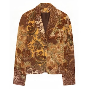 May include: A long-sleeve blazer featuring a multi-patterned design in shades of mustard yellow, brown, and cream. The garment displays a mix of floral, paisley, and animal print motifs, a notched lapel, two front buttons, and two flap pockets.