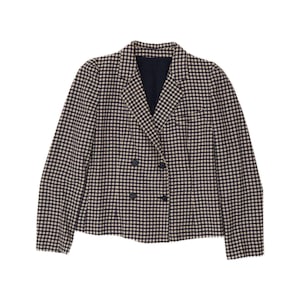 Op de afbeelding: Een double-breasted blazer met een zwart en crème gingham ruitpatroon. Het jasje heeft lange mouwen, een reverskraag en vier donkere knopen die in twee verticale rijen aan de voorzijde zijn geplaatst. De binnenvoering is effen zwart.