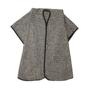 Puede incluir: Un poncho moteado en gris y blanco con un borde negro a lo largo de los contornos y una abertura en forma de lágrima en el cuello. La prenda presenta una silueta amplia y acampanada con mangas cortas y un patrón de tejido texturizado.