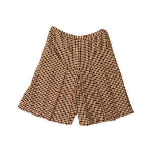 Pode incluir: Uma saia plissada com um padrão de xadrez castanho e preto. A peça tem uma cintura subida e uma silhueta rodada que se estende até à bainha, com pregas verticais na parte da frente para criar um aspeto estruturado e uniforme.