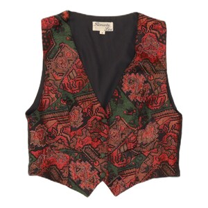 Può includere: Un gilet senza maniche con un vivace motivo in stile arazzo nei toni del rosso, verde e nero. Il capo presenta uno scollo a V, una chiusura frontale con tre bottoni e una fodera interna nera con un'etichetta che riporta Romantic Line.