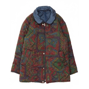 May include: A quilted jacket with a colorful geometric pattern in shades of red, green, blue, and purple. The jacket has a blue collar, a zipper closure, and snap buttons. It features two front pockets.