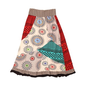 May include: A patchwork skirt featuring a variety of patterns and colors. The skirt has a cream-colored base with circular designs in shades of blue, red, and green. Red and black polka dot panels are on the sides, with a patterned waistband.