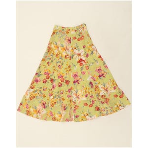 Puede incluir: Falda larga y fluida con un vibrante estampado floral. La falda presenta un fondo verde claro adornado con una mezcla de flores rosas, amarillas y rojas. La falda tiene un diseño escalonado y una cómoda cintura elástica.