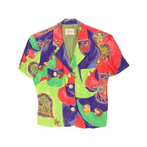 May include: A short-sleeved blazer featuring a vibrant, multicoloured abstract print in shades of lime green, royal blue, and red. The garment includes a notched lapel, two front patch pockets, and four gold-toned buttons. A label reads Vladím.