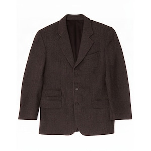 May include: A dark brown blazer featuring a textured fabric, a notched lapel, and a three-button front closure. The garment includes a single chest pocket, two lower flap pockets, and an additional small flap pocket above the right lower pocket.