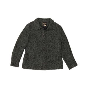 May include: A long-sleeve jacket featuring a textured black and white speckled pattern. The jacket has a standard collar, a front button closure with dark buttons, and a label inside the neckline that reads "Sportmaster".