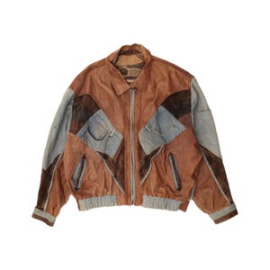 May include: Brown leather jacket with denim patchwork design. The jacket features a collared neckline, a zip-up front, and two front pockets. The sleeves and hemline have a ribbed knit trim.