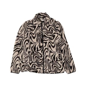 Puede incluir: Una chaqueta de manga larga con cremallera hecha de un material polar texturizado y difuso. La prenda presenta un cuello alto y un patrón ondulado y jaspeado de color negro y crema que se repite por toda la superficie exterior.