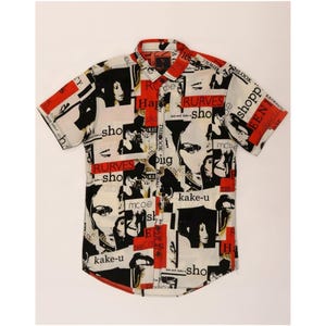 May include: A short-sleeved button-down shirt featuring a collage-style print with black and white portraits, red rectangular accents, and scattered text including "RURVES", "sho", "kake-u", and "mcoe" on a cream-coloured background with a collar.