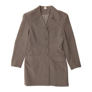 May include: A long-sleeved, taupe-coloured blazer featuring a notched lapel collar, a four-button front closure, and two rectangular flap pockets at the waist. The garment is constructed with vertical seams that provide a structured, tailored fit.