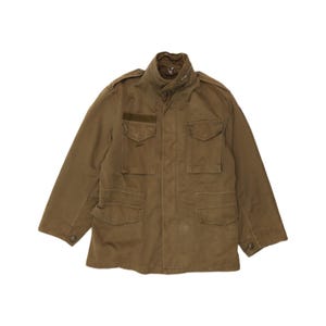 May include: A brown field jacket featuring a high collar with a zipper, two chest pockets with flaps, two lower pockets with flaps, shoulder epaulets, and buttoned cuffs. The jacket has a structured design with a central front placket closure.