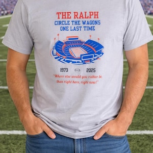 Man wearing a gray Buffalo Bills shirt featuring “The Ralph – Circle the Wagons One Last Time” stadium graphic with 1973–2025 tribute, standing on a football field background.