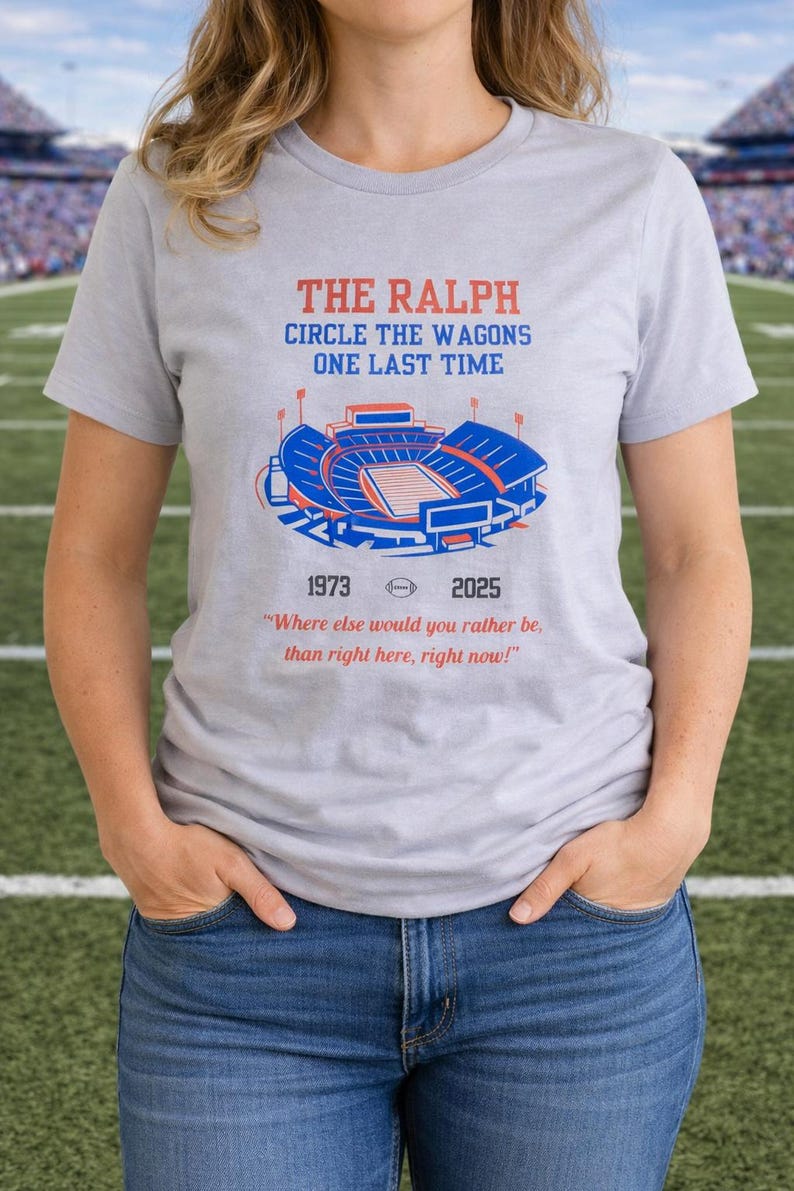 Woman wearing a gray Buffalo Bills shirt featuring “The Ralph – Circle the Wagons One Last Time” stadium graphic with 1973–2025 tribute, standing on a football field background.