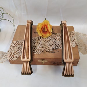 May include: Two vintage cabinet pulls with a cream colored plastic body and a gold metal base. The pulls are on a wooden box with a lace doily.