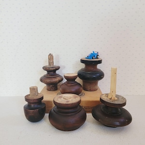 Puede incluir: Una colección de patas de muebles antiguos de madera en varias formas y tamaños. Las patas están teñidas en tonos de marrón y madera oscura. Un pequeño coche de juguete azul se encuentra encima de una de las patas. Las patas se exhiben en una caja de madera.