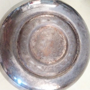 May include: Close-up of the bottom of a silver-plated cup with the words "PRINCESS" and "USA" engraved on the bottom.