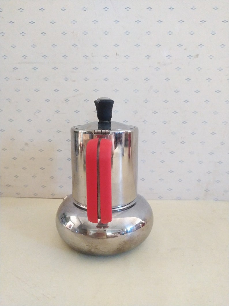May include: A silver and red stovetop espresso maker with a red handle.