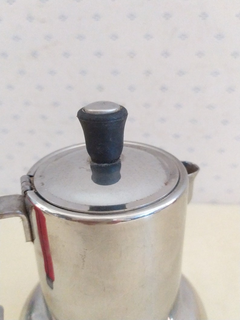 May include: A silver stainless steel coffee pot with a black plastic lid knob.