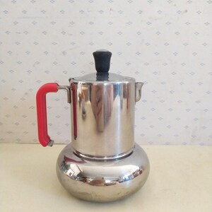 May include: A silver and red stovetop espresso maker with a rounded base and a black knob on the lid.
