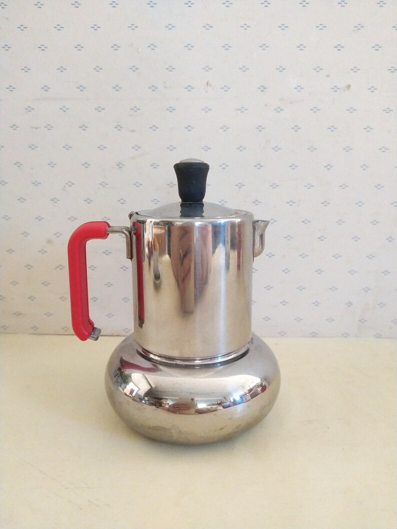 May include: A silver and red stovetop espresso maker with a rounded base and a black knob on the lid.