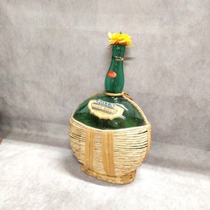Vintage green glass bottle with straw, wicker flask