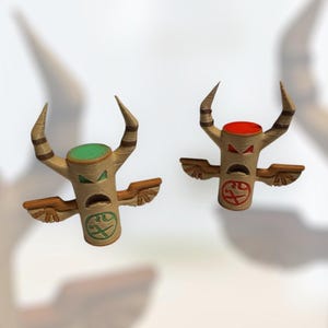 May include: Two wooden totem figures with wings and horns. The figure on the left has a green face and the figure on the right has a red face.