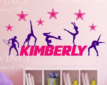 May include: Pink wall with a gymnastics themed wall decal featuring five female gymnasts in silhouette, a pink star design, and the name "KIMBERLY" in pink letters.