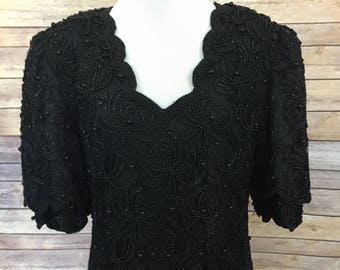 May include: A black beaded dress with a scalloped neckline and short sleeves. The dress is made of a sheer fabric and is covered in black beads.