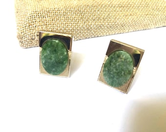 May include: A pair of cufflinks with a green stone set in a gold-toned metal frame.