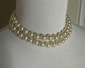 May include: A double strand of faux pearl necklace. The pearls are white and round.