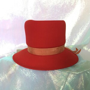 May include: A red felt hat with a wide brim and a brown ribbon around the crown.