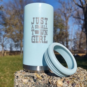 May include: A light blue stainless steel tumbler with a lid. The tumbler has the text "Just a small town girl" with a silhouette of the state of Arkansas.