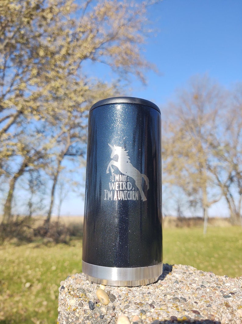 May include: A black and silver insulated tumbler with a glitter finish. The tumbler has a unicorn graphic and the text "I'm not weird, I'm a unicorn".