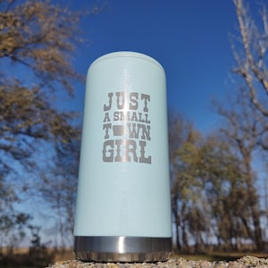 May include: A light blue stainless steel tumbler with a silver lid. The tumbler has the text "JUST A SMALL TOWN GIRL" printed on the side.