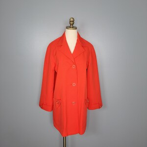 May include: A bright orange long-sleeved jacket with a button closure and two pockets. The jacket is on a mannequin.