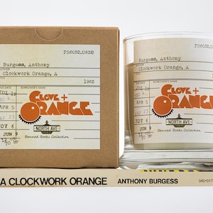Peut inclure: Une bo&icirc;te en carton marron et un pot en verre transparent avec une &eacute;tiquette qui indique "Clove + Orange" et "Banned Books Collection". L'&eacute;tiquette comprend &eacute;galement le titre du livre "Clockwork Orange, A" et l'auteur "Anthony Burgess". L'ann&eacute;e 1962 est imprim&eacute;e sur l'&eacute;tiquette.