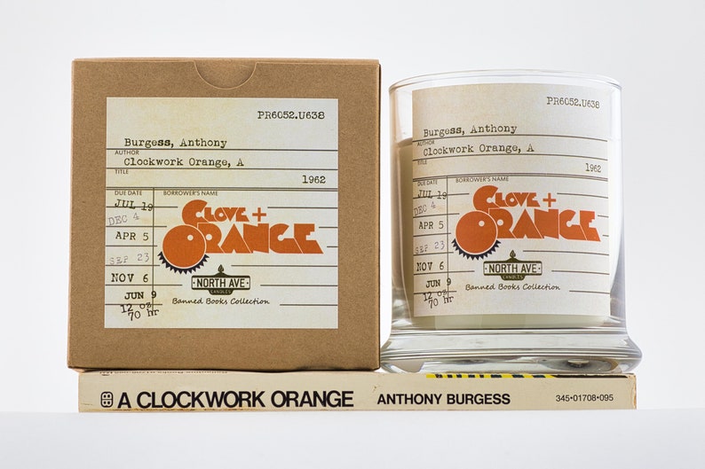 Peut inclure: Une bo&icirc;te en carton marron et un pot en verre transparent avec une &eacute;tiquette qui indique "Clove + Orange" et "Banned Books Collection". L'&eacute;tiquette comprend &eacute;galement le titre du livre "Clockwork Orange, A" et l'auteur "Anthony Burgess". L'ann&eacute;e 1962 est imprim&eacute;e sur l'&eacute;tiquette.