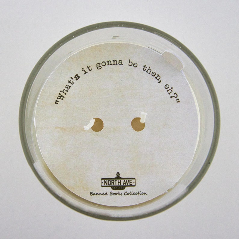 Peut inclure: Un bocal de bougie blanc avec une &eacute;tiquette qui dit "What's it gonna be then, eh?" et "North Ave Candles Banned Books Collection".