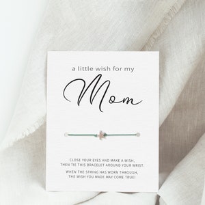 May include: A white card with the text "a little wish for my Mom" and a green string bracelet with a silver star charm. The card instructs the user to close their eyes, make a wish, tie the bracelet around their wrist, and when the string wears through, the wish may come true.