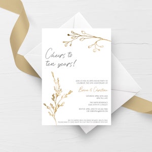 May include: A white invitation card with gold lettering and floral illustrations. The text reads "Cheers to ten years!" and includes details for an open house party to celebrate the 10th anniversary of Brian & Christina. The party is scheduled for Saturday, April 30th, 2023, from 6 PM till late at The Smith Residence, 12345 211th St, Langley. RSVP by April 22nd to 123-456-7890 or ChristinaG@RSVP.com.