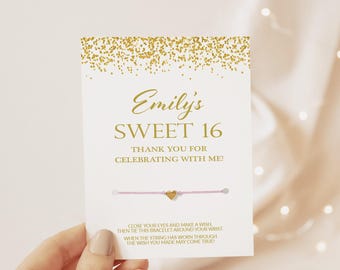 May include: A white card with gold glitter at the top, featuring the text Emily's SWEET 16 THANK YOU FOR CELEBRATING WITH ME! and a light pink string bracelet with a small gold heart charm attached to the center of the card.