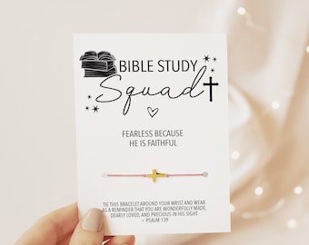 Op de afbeelding: Een roze koordarmband met een gouden kruisbedel. De kaart heeft de tekst "Bible Study Squad" met een hartje en sterren. Er staat ook "Fearless because He is Faithful" en "Bind deze armband om je pols en draag hem als een herinnering dat je wonderbaarlijk gemaakt bent, innig geliefd en kostbaar in zijn ogen. - Psalm 139"