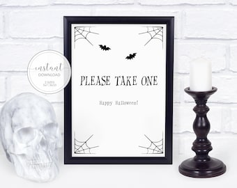 May include: A black framed sign with white background featuring black spider web corner illustrations, two small black bats, and the text "PLEASE TAKE ONE" above "Happy Halloween!" next to a white skull and a black candle holder.