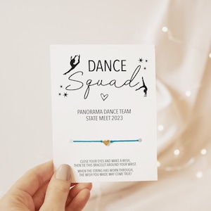 May include: A blue string bracelet with a gold heart charm. The card reads "Dance Squad" with a silhouette of a dancer. The card also says "Panorama Dance Team State Meet 2023".