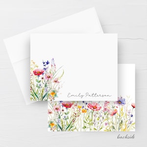 May include: A white stationery card and matching envelope featuring a watercolour illustration of colourful wildflowers in shades of pink, red, yellow, and blue. The card displays the name Emily Patterson in black script text.
