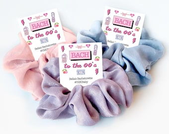 May include: Three fabric hair scrunchies in light pink, light blue, and lavender. Each is attached to a white card featuring the text BACH to the 00's, Bella's Bachelorette, and #Y2KBaby, decorated with pink icons of hearts, butterflies, and cherries.