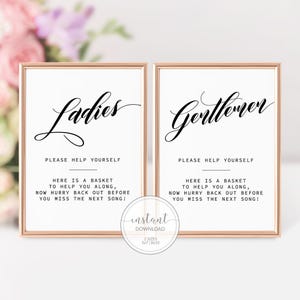 May include: Two rectangular signs in rose gold frames with white backgrounds and black text. One sign reads Ladies, the other Gentlemen. Both include the text: Please help yourself. Here is a basket to help you along, now hurry back out before you miss the next song!